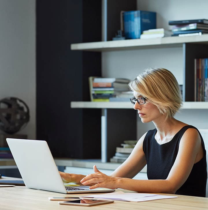 Businesswoman using laptop at desk. Confident female professional is working in textile factory. Executive is with short brown hair.