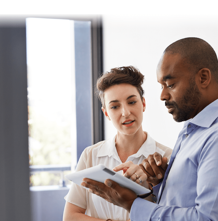 Coworkers standing up and looking at tablet together